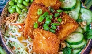 Overhead view of crunchy Asian salad with crispy fish, topped with toasted ramen crunchies and tangy dressing