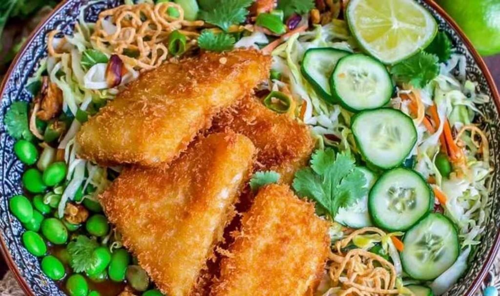 Overhead view of crunchy Asian salad with crispy fish, topped with toasted ramen crunchies and tangy dressing
