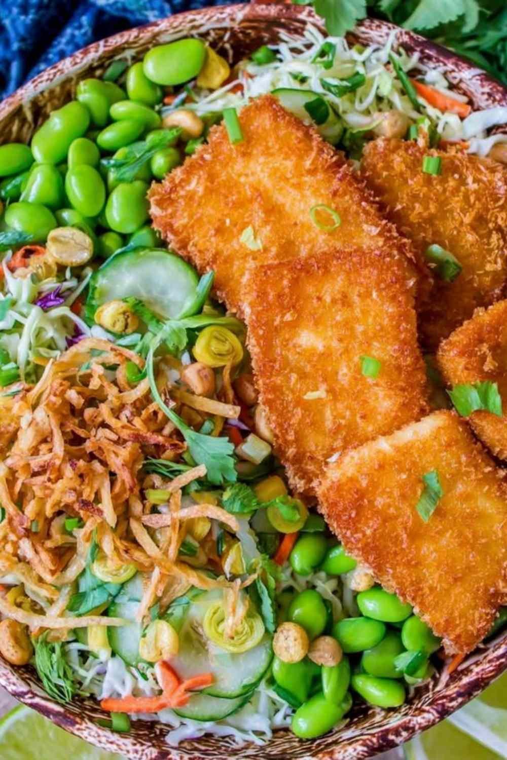 Overhead view of crunchy Asian salad with crispy fish, topped with toasted ramen crunchies and tangy dressing