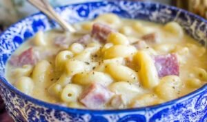 Creamy ham mac and cheese soup in a white bowl with chunks of diced ham and tender macaroni noodles