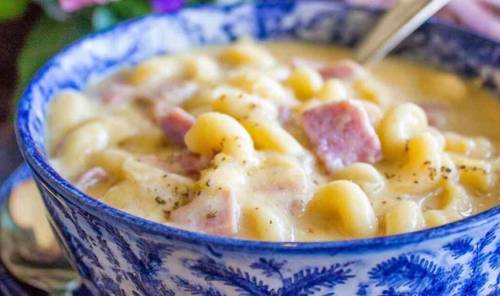 Creamy ham mac and cheese soup in a white bowl with chunks of diced ham and tender macaroni noodles
