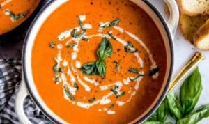 A bowl of creamy homemade tomato soup topped with fresh basil and a swirl of heavy cream