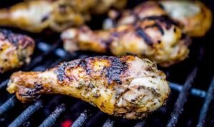 Seasoned chicken drumsticks and bone-in thighs on a plate ready to make lemon tarragon grilled chicken