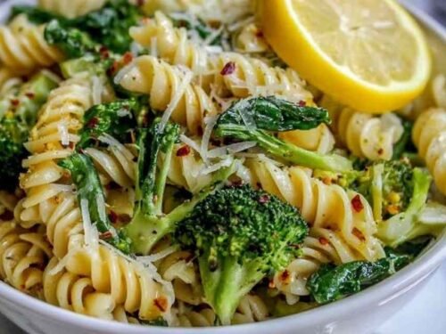 Lemon broccoli pasta in a skillet topped with freshly grated Parmesan and lemon wedges