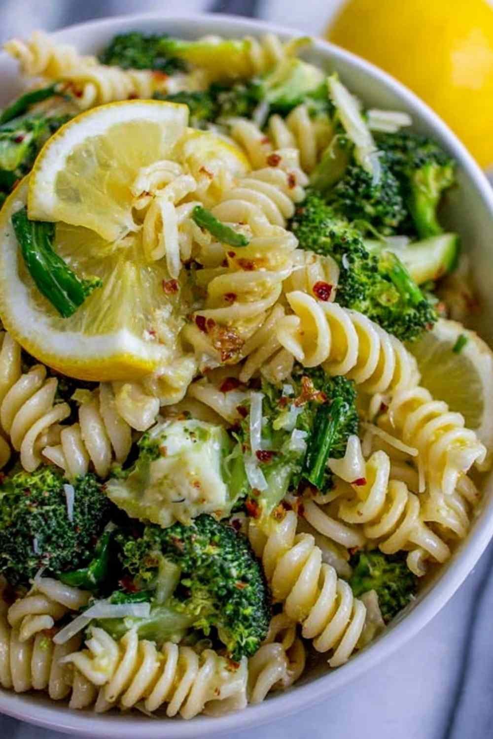 Lemon broccoli pasta in a skillet topped with freshly grated Parmesan and lemon wedges