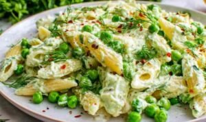 Lemon pasta with ricotta and fresh peas A white plate of lemon pasta with ricotta and fresh peas topped with toasted pine nuts and Parmesan cheese