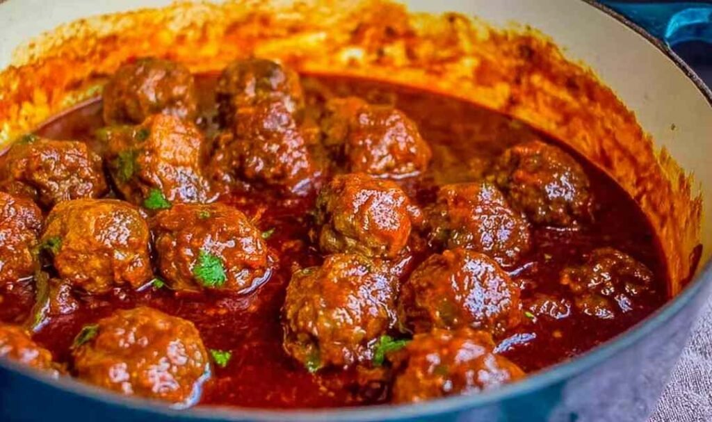 Easy baked Mexican meatballs covered in thick red enchilada sauce and garnished with fresh cilantro, served with cilantro lime rice and pinto beans