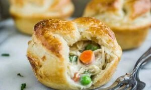 Uncooked mini chicken pot pies in a greased muffin tin ready for the oven