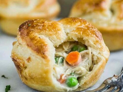 Uncooked mini chicken pot pies in a greased muffin tin ready for the oven