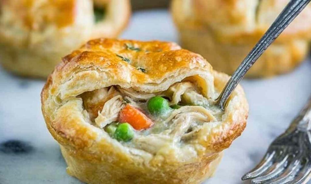 Uncooked mini chicken pot pies in a greased muffin tin ready for the oven