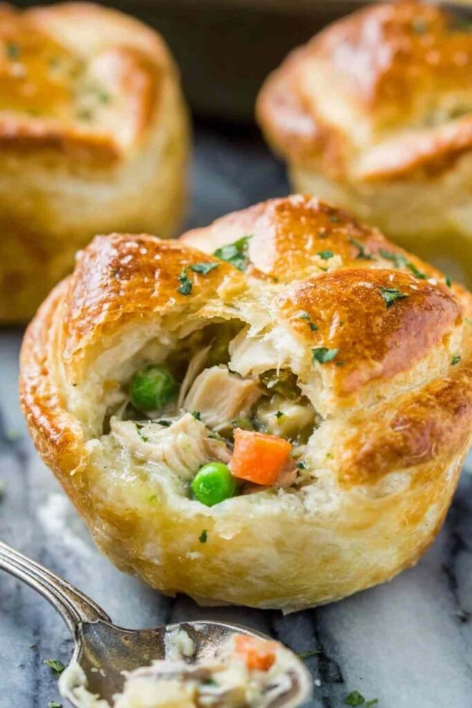 Uncooked mini chicken pot pies in a greased muffin tin ready for the oven
