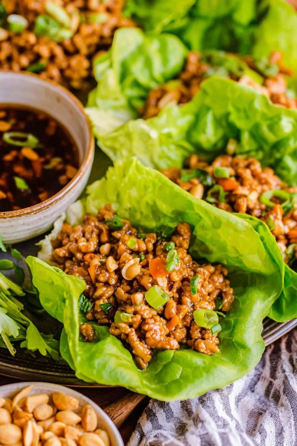 Copycat PF Chang's chicken lettuce wraps filled with diced chicken and shiitake mushrooms served on a white plate with Asian dipping sauce