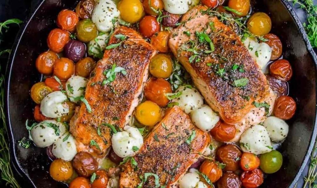 Pan-seared salmon with cherry tomatoes and mozzarella in a cast iron skillet
