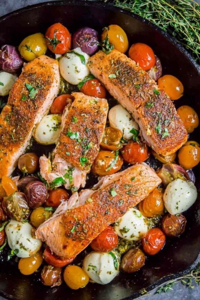 Pan-seared salmon with cherry tomatoes and mozzarella in a cast iron skillet