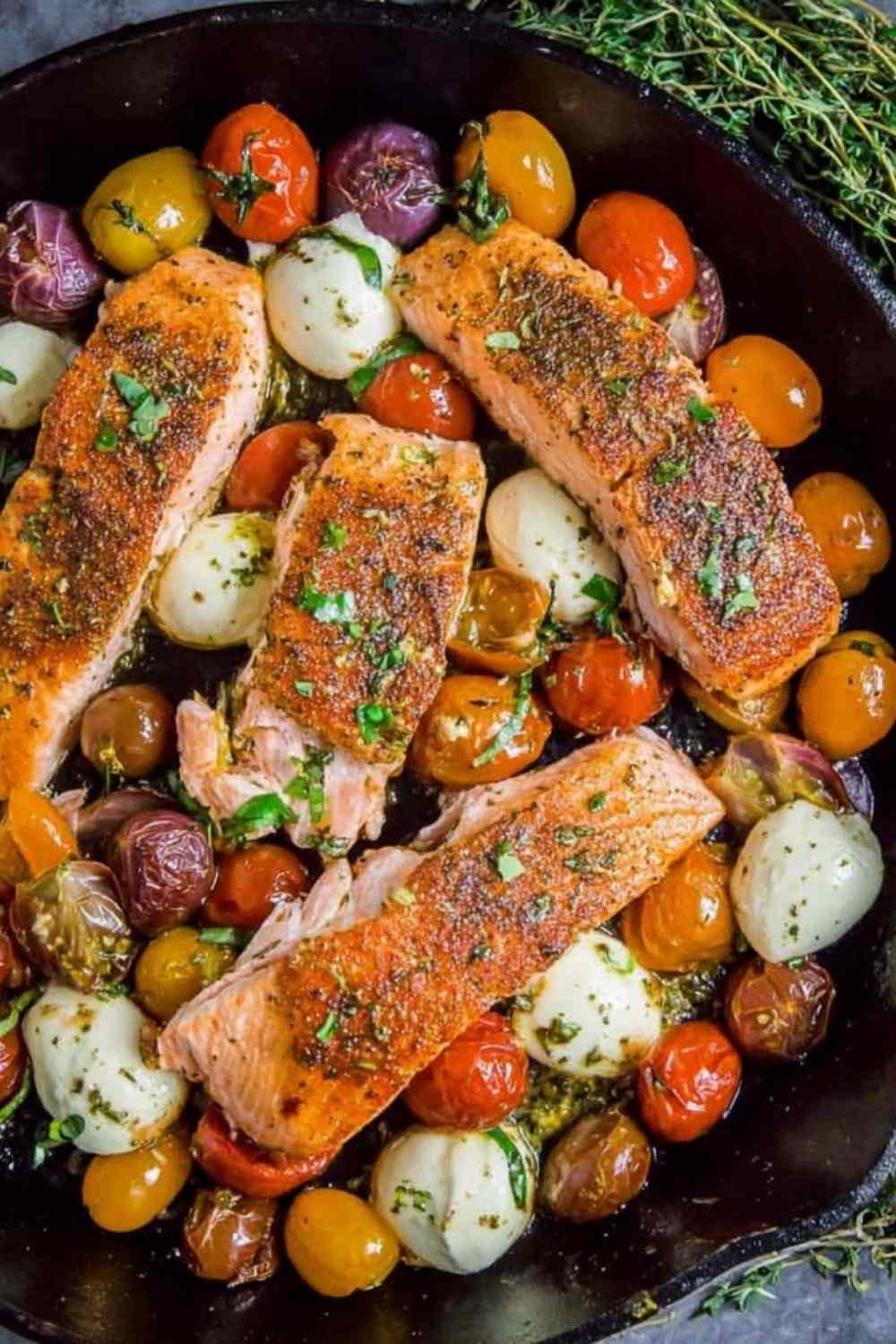 Pan-seared salmon with cherry tomatoes and mozzarella in a cast iron skillet
