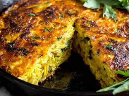 Golden pasta frittata with sausage and parmesan in a nonstick skillet, crispy edges visible