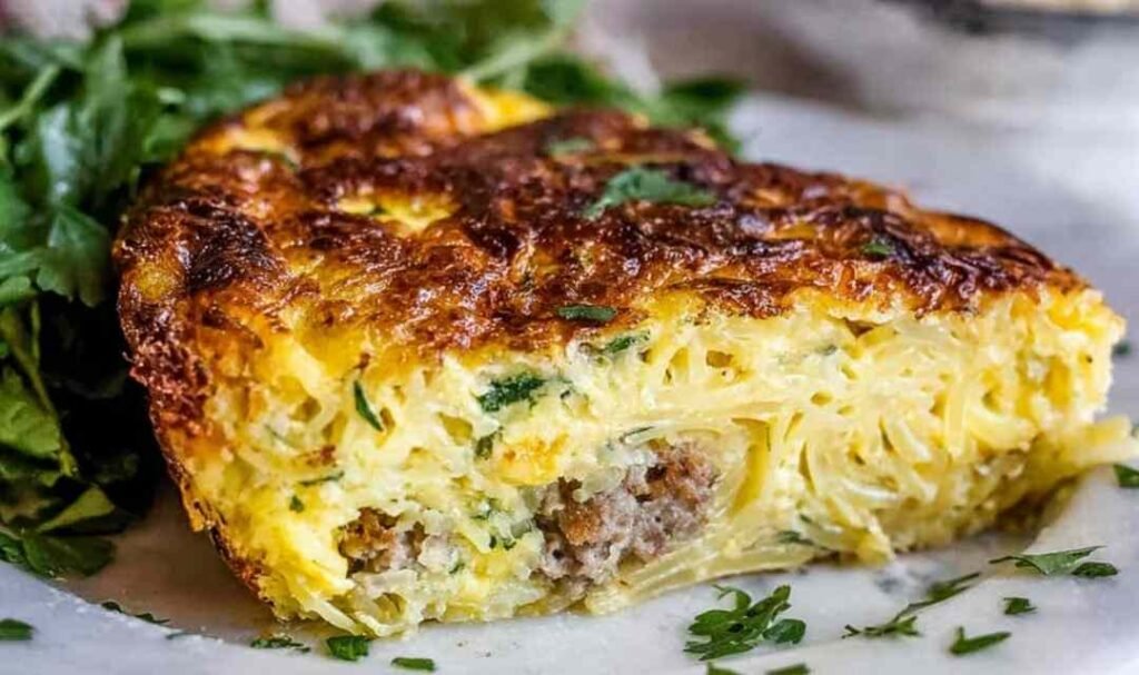 Golden pasta frittata with sausage and parmesan in a nonstick skillet, crispy edges visible