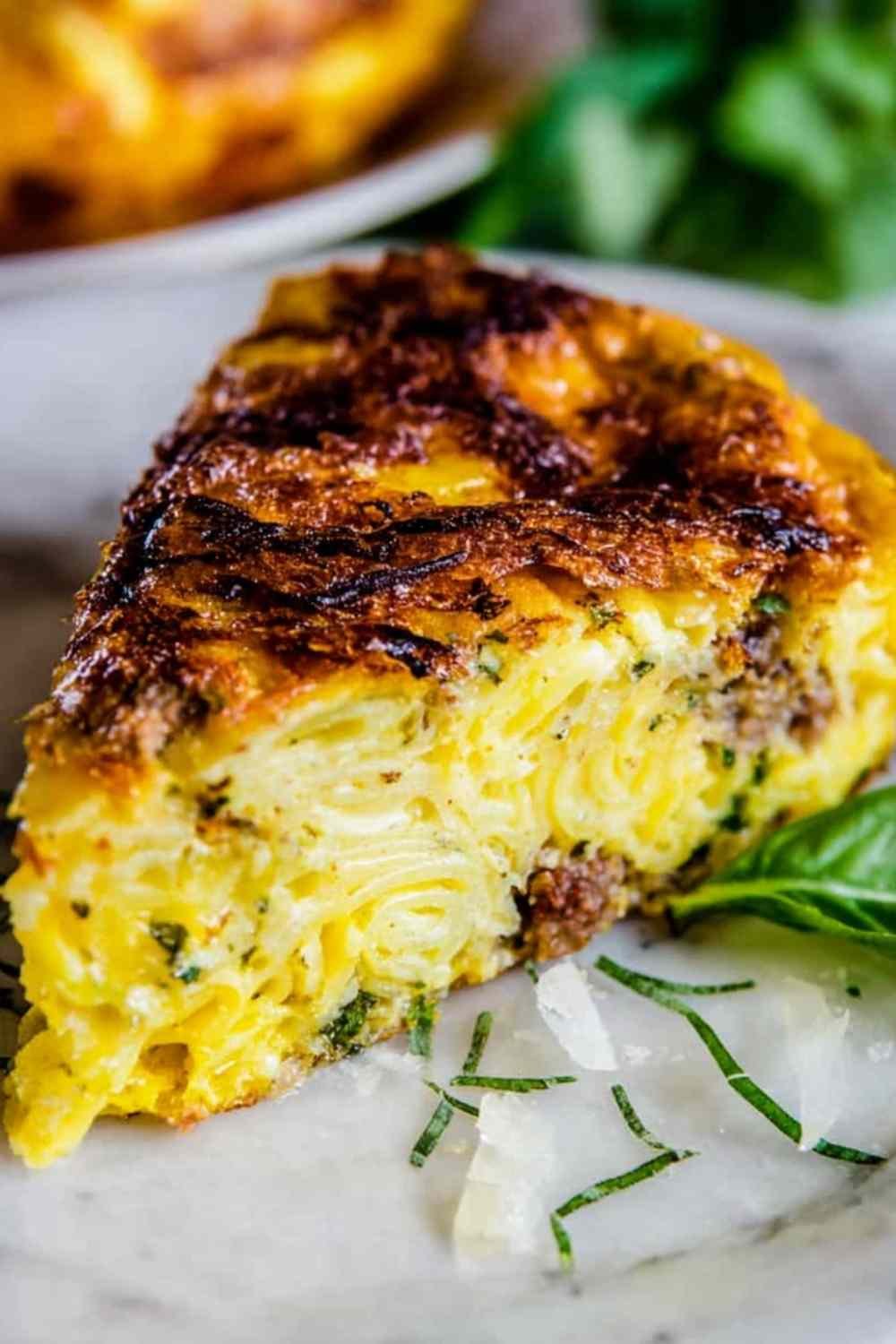 Golden pasta frittata with sausage and parmesan in a nonstick skillet, crispy edges visible
