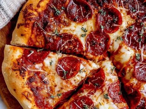 Hands kneading a smooth pizza dough recipe in a bowl.