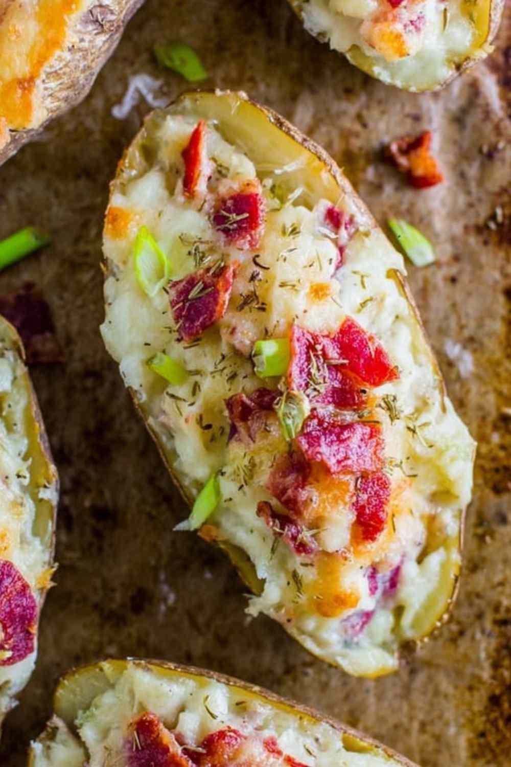 Reuben stuffed twice baked potatoes topped with melted Swiss cheese and garnished with chopped dill pickles on a greased sheet pan