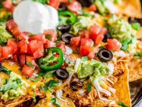 Easy rotisserie chicken nachos loaded with melted cheese and black beans fresh from the oven on a sheet pan
