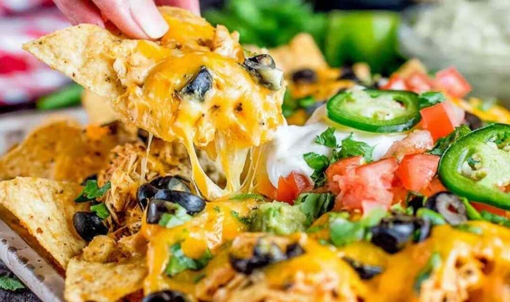 Easy rotisserie chicken nachos loaded with melted cheese and black beans fresh from the oven on a sheet pan