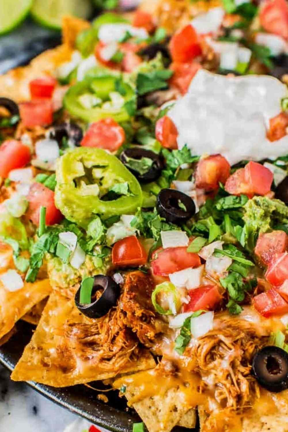 Easy rotisserie chicken nachos loaded with melted cheese and black beans fresh from the oven on a sheet pan