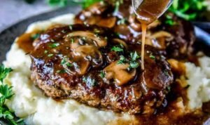 Homemade Salisbury steak recipe with mushroom gravy simmering in a cast iron skillet garnished with fresh parsley