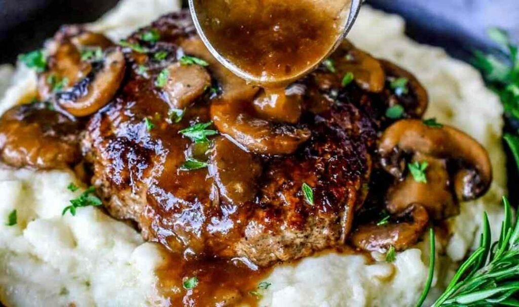 Homemade Salisbury steak recipe with mushroom gravy simmering in a cast iron skillet garnished with fresh parsley