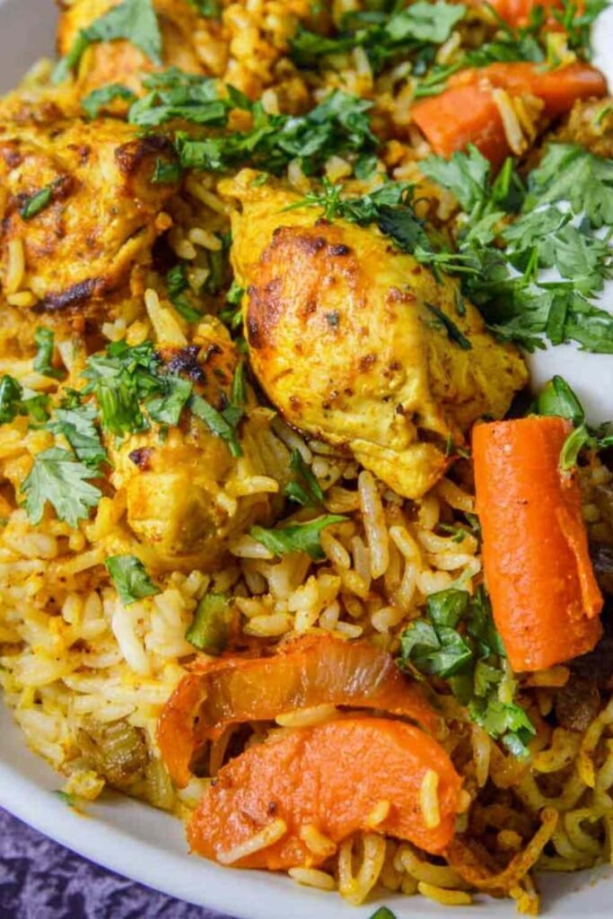 Sheet pan curry chicken with roasted carrots, basmati rice, cashews, and cilantro on a rimmed baking sheet
