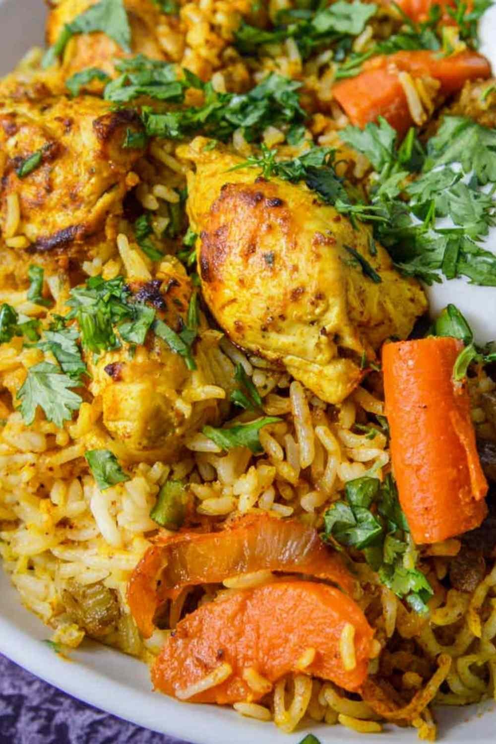 Sheet pan curry chicken with roasted carrots, basmati rice, cashews, and cilantro on a rimmed baking sheet