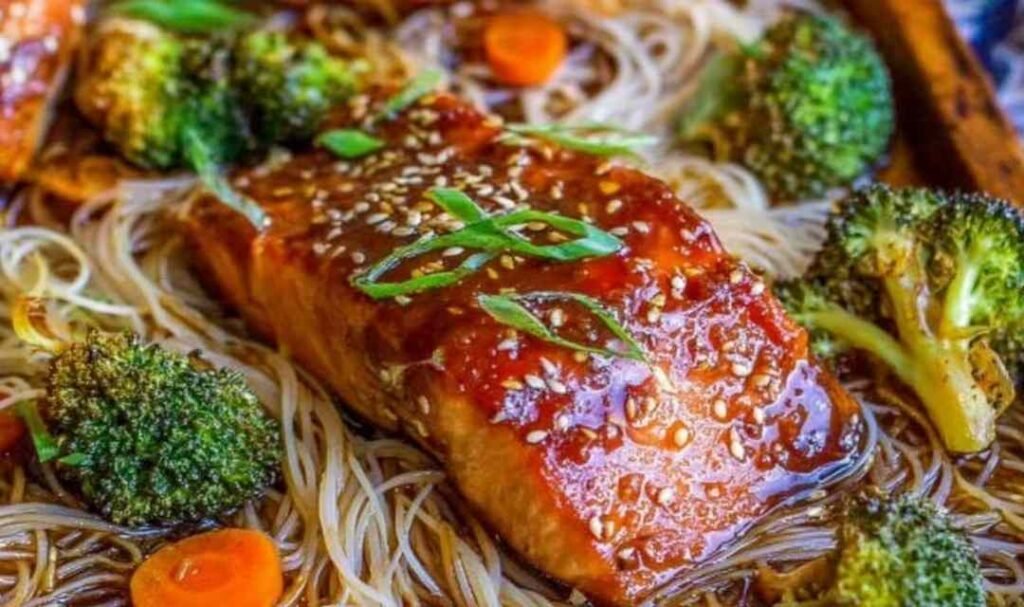 Sheet pan Asian salmon with broccoli and carrots roasted in soy ginger sauce on a rimmed sheet pan