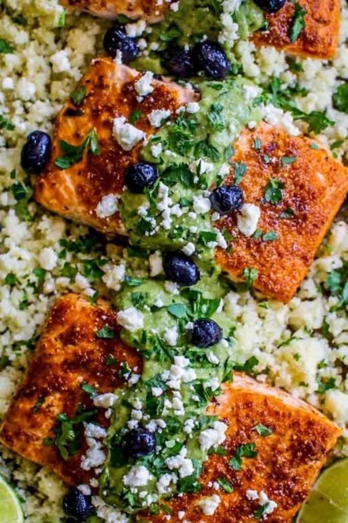 Sheet pan honey chipotle salmon with cauliflower rice, black beans, and avocado coconut cream on a baking sheet