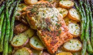 Overhead view of sheet pan salmon with creamy scalloped potatoes and asparagus on a rimmed baking sheet with citrus glaze