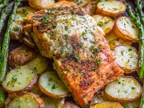 Overhead view of sheet pan salmon with creamy scalloped potatoes and asparagus on a rimmed baking sheet with citrus glaze