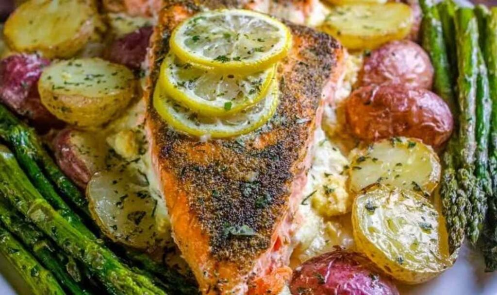 Overhead view of sheet pan salmon with creamy scalloped potatoes and asparagus on a rimmed baking sheet with citrus glaze