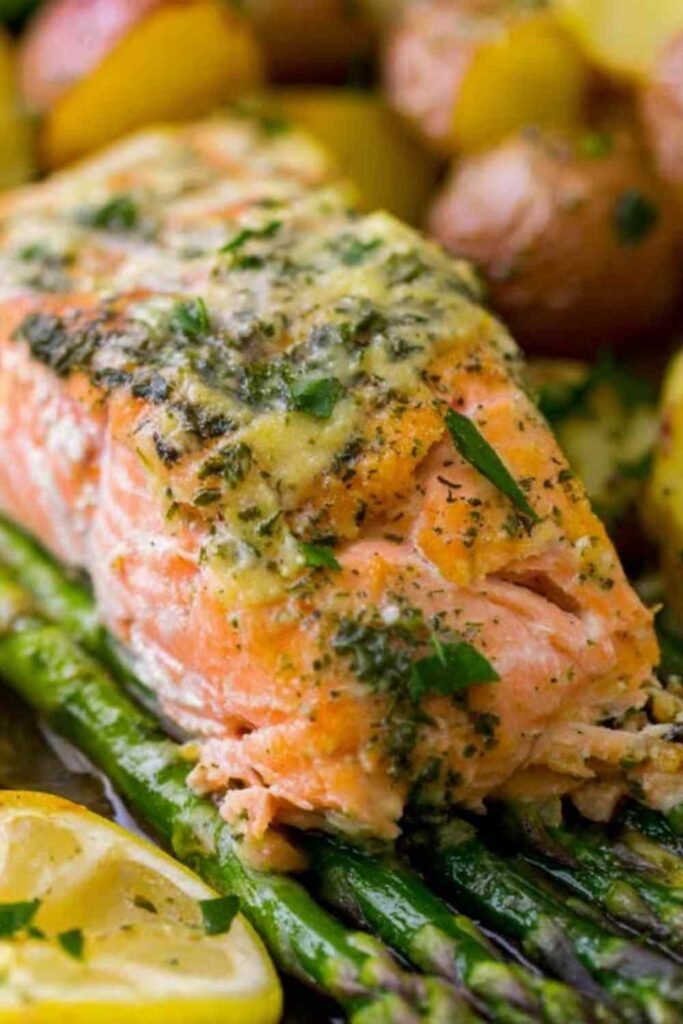 Overhead view of sheet pan salmon with creamy scalloped potatoes and asparagus on a rimmed baking sheet with citrus glaze