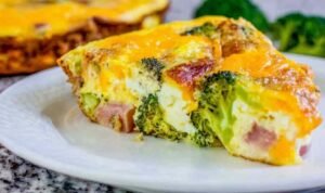cheesy ham and broccoli frittata Cheesy ham and broccoli frittata in a cast iron skillet with golden brown top and visible cheddar cheese pockets
