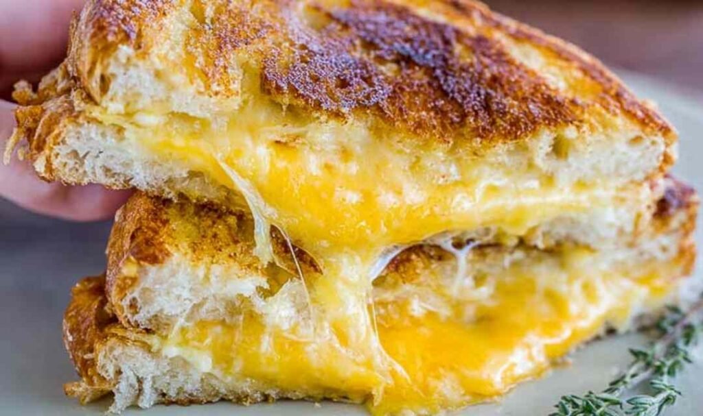 Best grilled cheese recipe pulled apart to show melty cheddar cheese stretch with crispy golden challah bread