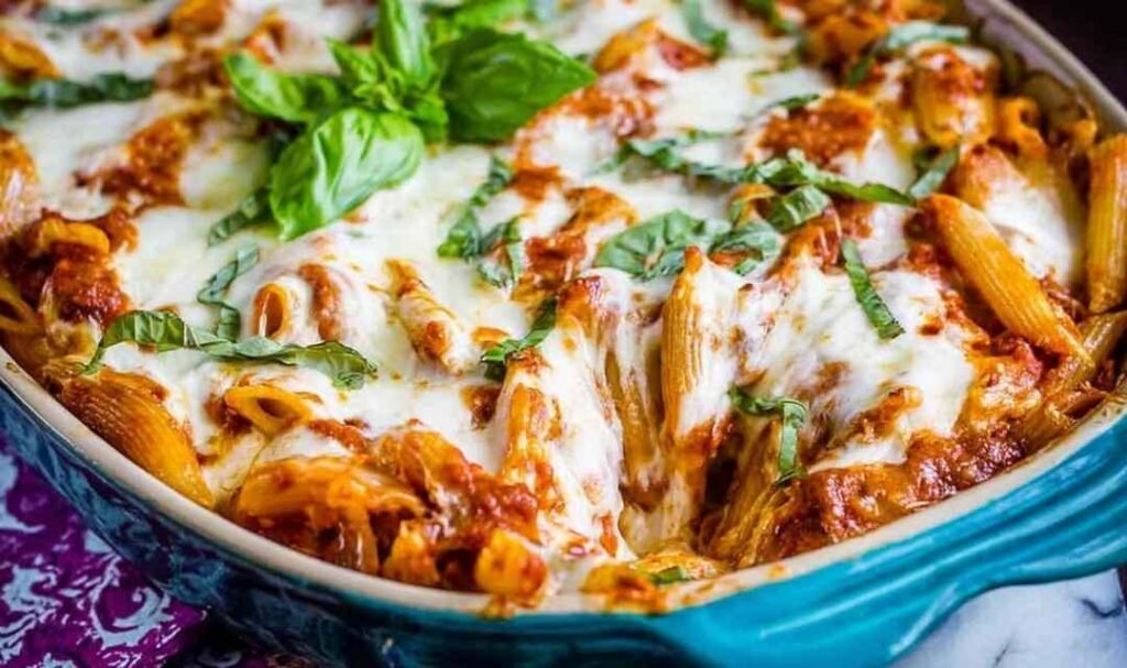 Extra cheesy penne and mozzarella casserole in a 9x13 baking dish with golden bubbly cheese across the top