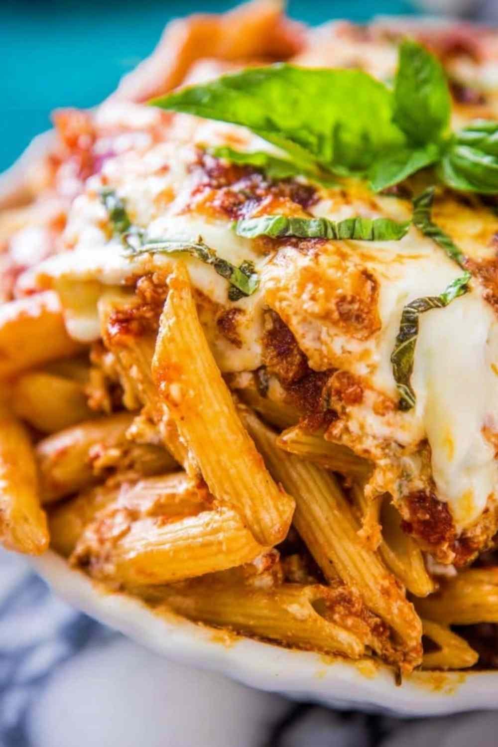 Extra cheesy penne and mozzarella casserole in a 9x13 baking dish with golden bubbly cheese across the top