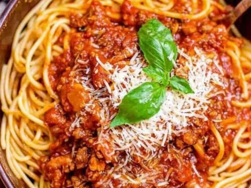 Ingredients for easy spaghetti sauce including sausage and marinara in a Dutch oven