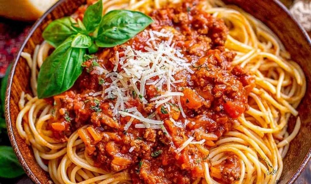 Ingredients for easy spaghetti sauce including sausage and marinara in a Dutch oven